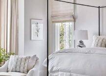 Restful bedroom is complemented with a white and green upholstered bed placed at the foot of a black canopy bed contrasted with a white duvet.