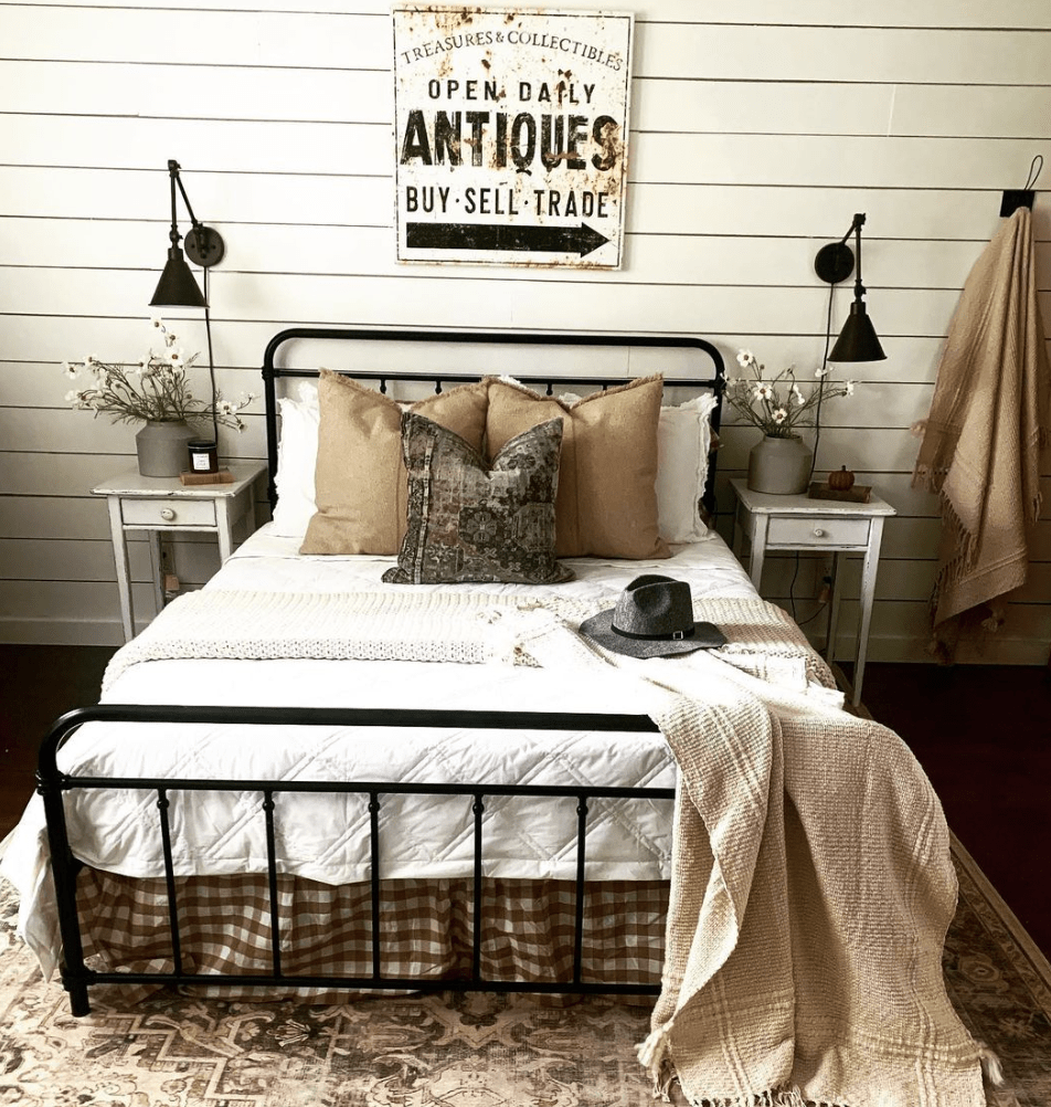 vintage sign in bedroom hanging above bed antiques white bedding black iron bed wall sconces